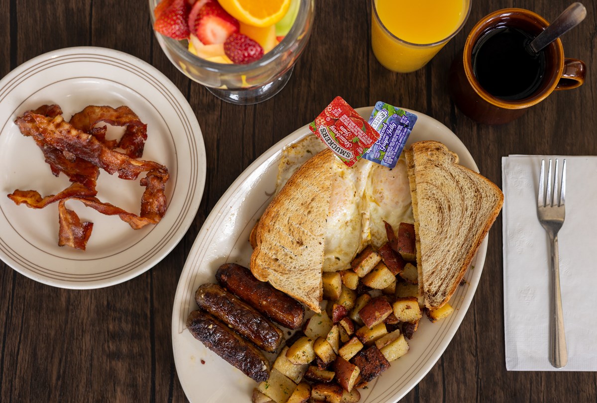 Two eggs, sausage links, home fries, toast, and side of bacon.